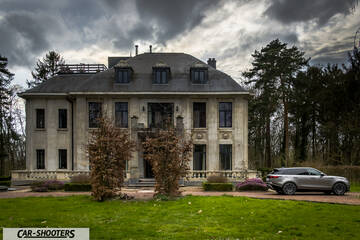rear three-quarter, silver in front of a large mansion
