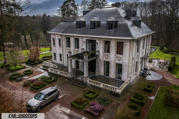 front three-quarter, silver parked near a large mansion