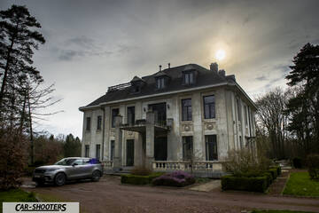 front three-quarter, silver in front of a large mansion