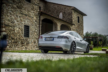 Tesla Model S – rear three-quarter, silver parked in front of a stone building
