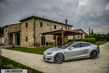 Tesla Model S – front three-quarter, silver metallic in front of a stone building