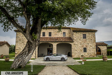 Tesla Model S – side profile, silver in front of a stone villa