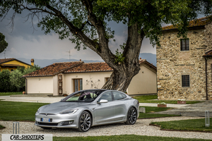 Tesla Model S – front three-quarter, silver parked near a historic stone building