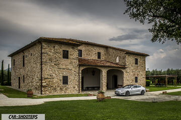 Tesla Model S – front three-quarter, silver parked in front of a stone building
