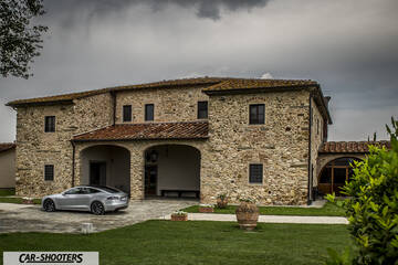 Tesla Model S – rear three-quarter, silver in front of a stone building