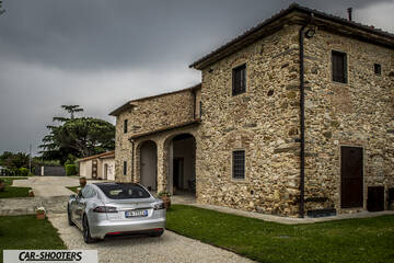 Tesla Model S – rear three-quarter, silver parked near an old stone building