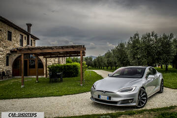 Tesla Model S – front three-quarter, silver parked near a stone house