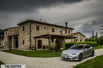 Tesla Model S – front three-quarter, silver against a rustic stone villa