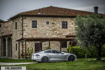 Tesla Model S – rear three-quarter, silver parked in front of a stone building