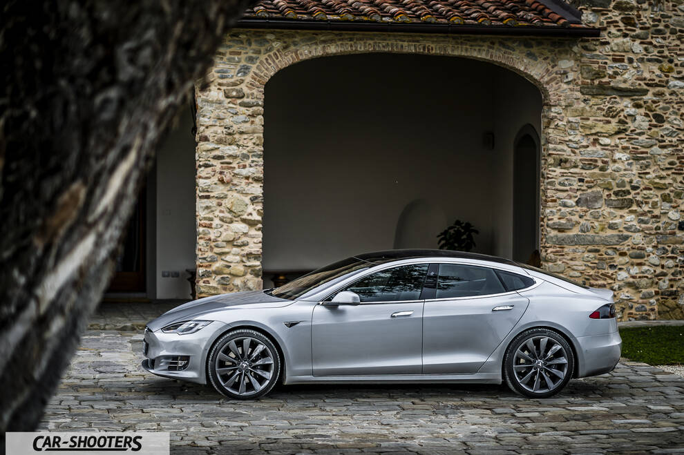 Tesla Model S – side profile, silver parked in front of a stone building