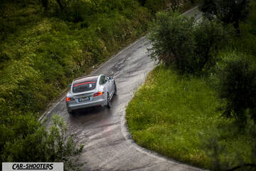 Tesla Model S – rear three-quarter, silver on a winding country road