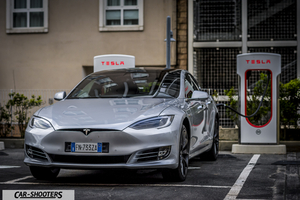 Tesla Model S – front three-quarter, silver metallic at a tesla supercharger station