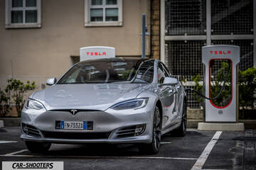 Tesla Model S – front three-quarter, silver metallic at a tesla supercharger station