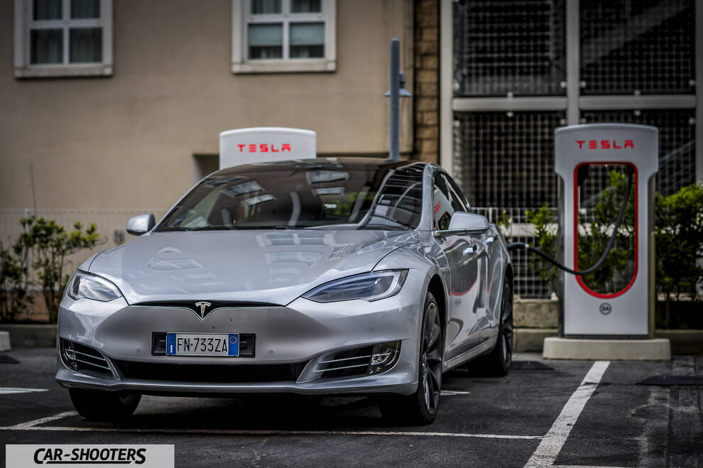 Tesla Model S – front three-quarter, silver metallic at a tesla supercharger station