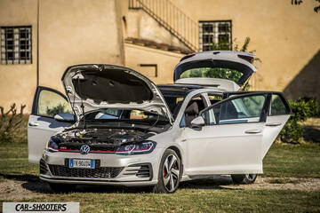 Volkswagen Golf GTI – front three-quarter, white with doors and hood open on grass