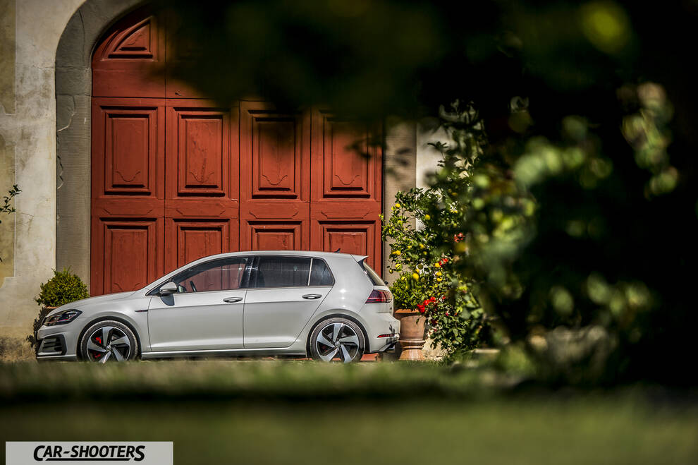 Volkswagen Golf GTI – side profile, white against a large red wooden door