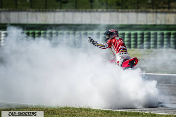 rear three-quarter, red surrounded by tire smoke on a racetrack
