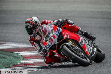 front three-quarter, red cornering on a race track