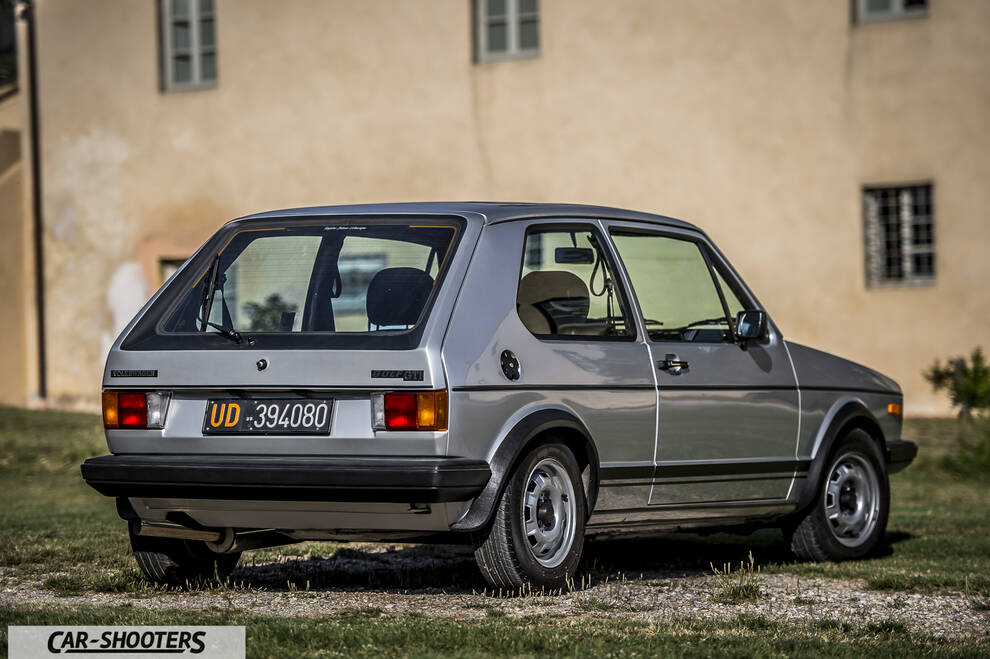 rear three-quarter, silver against a rustic building wall