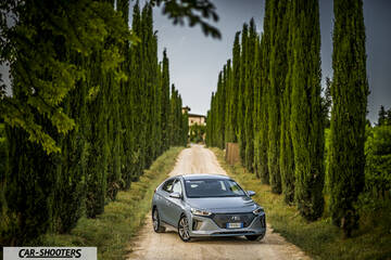 Hyundai Ioniq – front three-quarter, silver on a dirt road lined with tall trees