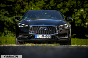Infiniti Q60 – front three-quarter, black against a blurred green background