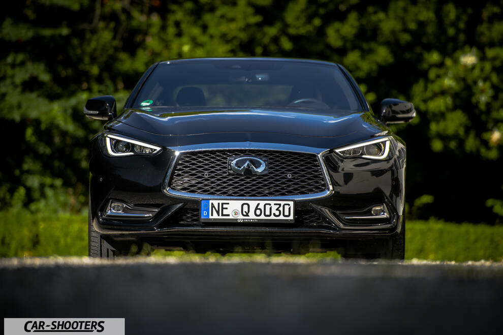Infiniti Q60 – front three-quarter, black against a blurred green background