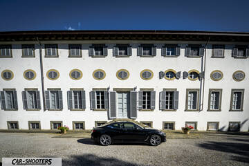 Infiniti Q60 – side profile, black in front of a white building
