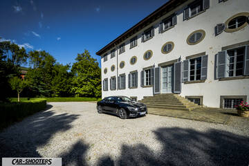 Infiniti Q60 – front three-quarter, black in a gravel courtyard
