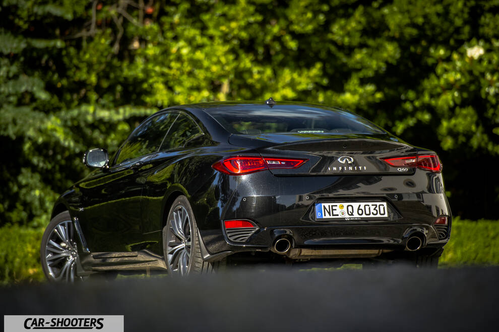 Infiniti Q60 – rear three-quarter, black against a green foliage background