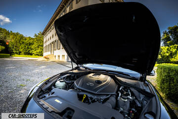 Infiniti Q60 – engine bay, open hood in front of a building