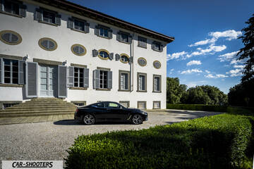 Infiniti Q60 – side profile, black parked in front of a large building