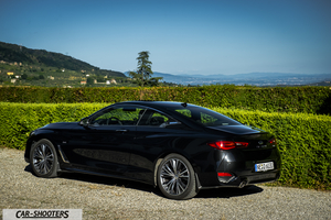 Infiniti Q60 – rear three-quarter, black against a mountain backdrop