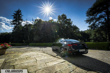 Infiniti Q60 – rear three-quarter, black in a sunny courtyard