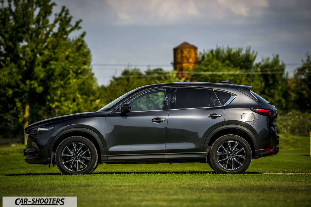 Mazda CX 5 – side profile, dark grey metallic parked on a grassy field
