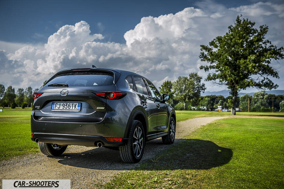 Mazda CX 5 – rear three-quarter, grey metallic on a dirt path by a grassy field