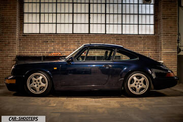 Porsche – side profile, dark blue in a brick garage