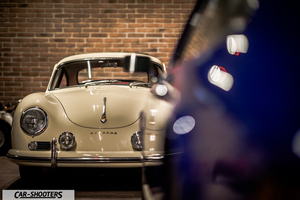 Porsche – front three-quarter, beige against a brick wall