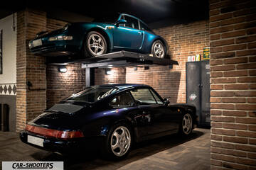 Porsche – rear three-quarter, dark blue in a brick garage with car lift