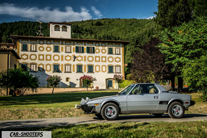 Fiat X1 9 Storia – side profile, silver on a country road against a large building backdrop