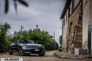 Mazda MX 5 Cherry Edition – front three-quarter, grey metallic on a gravel driveway next to a stone building