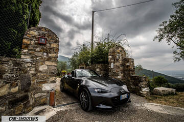 Mazda MX 5 Cherry Edition – front three-quarter, dark grey metallic in a stone gateway