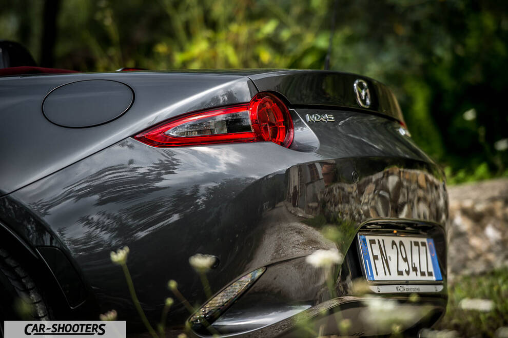 Mazda MX 5 Cherry Edition – rear three-quarter, dark grey metallic against a natural leafy backdrop