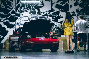 front three-quarter, red in a garage with people