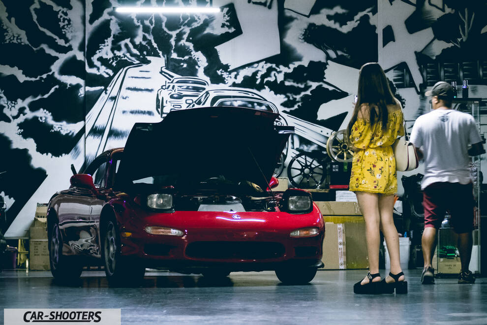 front three-quarter, red in a garage with people