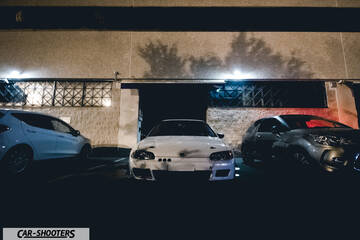 front three-quarter, white parked against a concrete wall