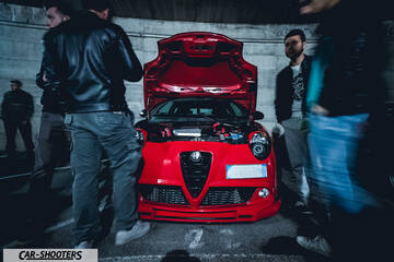 front three-quarter, red in a parking garage with people standing around