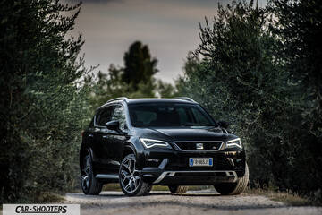 Seat Ateca – front three-quarter, black on a dirt road flanked by trees