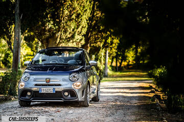 Abarth 695 Rivale – front three-quarter, silver and blue on a tree-lined dirt path