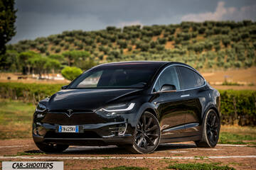 Tesla Model X – front three-quarter, black against a green hill backdrop