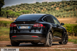 Tesla Model X – rear three-quarter, black against a hillside backdrop